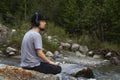 Young man in headphones listening music in nature and at the mountain