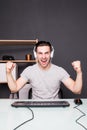 Young happy man with headset playing and winning computer game at home Royalty Free Stock Photo