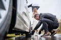 Young man helping beautiful woman to fix car on the road. Royalty Free Stock Photo