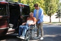 Young man helping patient in wheelchair to get into van Royalty Free Stock Photo