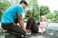 A young man helps hold the legs of a veiled girl doing sit ups while exercising outdoors