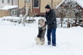 Young man with her dog husky outdoor on winter background. Active and happy man playing with dog, caressing and training Royalty Free Stock Photo