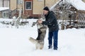 Young man with her dog husky outdoor on winter background. Active and happy man playing with dog, caressing and training Royalty Free Stock Photo