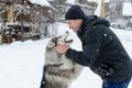 Young man with her dog husky outdoor on winter background. Active and happy man playing with dog, caressing and training Royalty Free Stock Photo