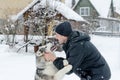 Young man with her dog husky outdoor on winter background. Active and happy man playing with dog, caressing and training Royalty Free Stock Photo