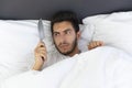 A young man is hiding in bed under a blanket at home Royalty Free Stock Photo