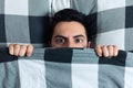 Young man hiding in bed under the blanket Royalty Free Stock Photo