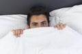 A young man is hiding in bed under a blanket at home Royalty Free Stock Photo