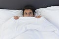 A young man is hiding in bed under a blanket at home Royalty Free Stock Photo