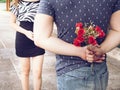 Young man hiding roses from his back and give them to his girlfriend
