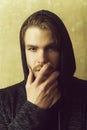 Young man hiding unshaven face with hand wearing grey hoodie