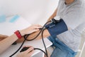 Young man with high blood pressure. Female doctor using sphygmomanometer with stethoscope checking blood pressure to a Royalty Free Stock Photo