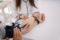 Young man with high blood pressure. Female doctor using sphygmomanometer with stethoscope checking blood pressure to a Royalty Free Stock Photo