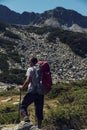 Young man hiking in the mountain in summer sunny day with red backpack Royalty Free Stock Photo