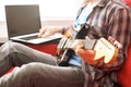 Casually dressed young man with guitar playing songs in the room at home. Online guitar lessons concept. Male guitarist practicing Royalty Free Stock Photo