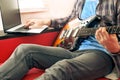 Casually dressed young man with guitar playing songs in the room at home. Online guitar lessons concept. Male guitarist practicing Royalty Free Stock Photo