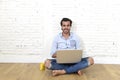 Young man in hipster modern casual style look sitting on living room home floor working on laptop