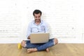 Young man in hipster modern casual style look sitting on living room home floor working on laptop Royalty Free Stock Photo