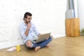 Young man in hipster modern casual style look sitting on living room home floor working on laptop