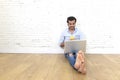 Young man in hipster modern casual style look sitting on living room home floor working on laptop Royalty Free Stock Photo