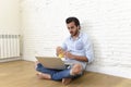 Young man in hipster modern casual style look sitting on living room home floor working on laptop Royalty Free Stock Photo