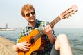 Young man hipster playing guitar by sea ocean Royalty Free Stock Photo