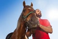 Young man with his bay horse against blue sky Royalty Free Stock Photo