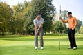 Young man with his friend playing golf in golf course Royalty Free Stock Photo