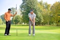 Young man with his friend playing golf in golf course Royalty Free Stock Photo