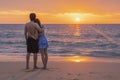 Young man and his girlfriend cuddle together on a beach with a sea back and a romantic sunset at Nai Thon Beach, Phuket, Thailand