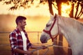 Young man and his horse starting the day together. Fun on countryside, sunset golden hour. Freedom nature concept