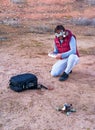 Young man on his knees with drone glasses, radio and drone in his hands, and backpack on the ground