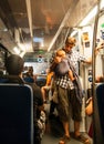 Young man and his little baby in sling in sunset lighting traveling in train car