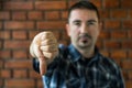 Young man in his 30s showing thumbs down. Selective focus