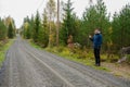 Young man hitchhiking on a finnish country road near the woods Royalty Free Stock Photo