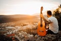 Young man holding acoustic guitar and looking to sunset.Searching inspiration.Music creator.New artist.Musical talent.