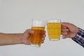 Young man holding beer glasses clashing in celebration with white background