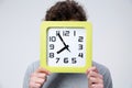 Young man holding a big clock covering his face Royalty Free Stock Photo