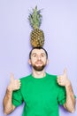 Young man holding big pineapple on his head Royalty Free Stock Photo