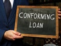 Young man holding a black chalkboard in hands. Conceptual photo about CONFORMING LOAN with written text