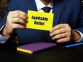 Young man holding a blank card in hands. Conceptual photo about Equitable Relief with written text