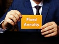 Young man holding a blank card in hands. Conceptual photo about Fixed Annuity with written text