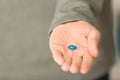 Young man holding blue pill, closeup Royalty Free Stock Photo