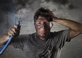 Young man holding cable smoking after electrical accident with dirty burnt face in funny sad expression Royalty Free Stock Photo