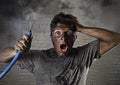 Young man holding cable smoking after electrical accident with dirty burnt face in funny sad expression Royalty Free Stock Photo