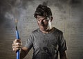 Young man holding cable smoking after electrical accident with dirty burnt face in funny sad expression Royalty Free Stock Photo