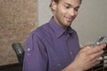 Young man Holding Cellphone In Office Royalty Free Stock Photo