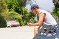 Young man holding cellphone sitting on park bench on sunny day Royalty Free Stock Photo