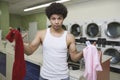 Young Man Holding Clothes At Launderette