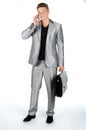 Young man with briefcase and cell phone standing against white background Royalty Free Stock Photo